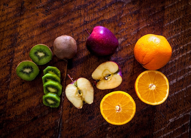 Maçã laranja e kiwi na mesa de madeira