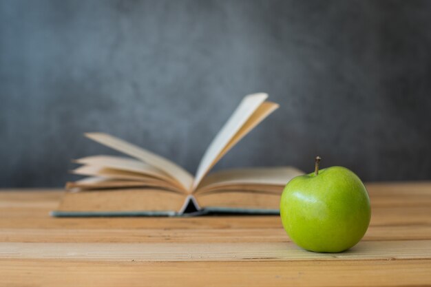 Maçã verde com livro de abertura na mesa de madeira