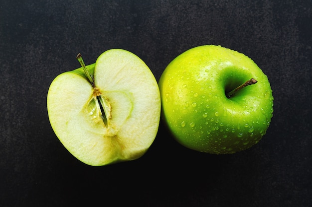 Maçã verde em uma superfície escura com gotas de água