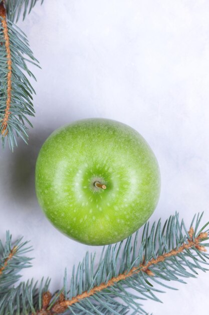 Maçã verde madura e suculenta com galhos de abeto em um fundo leve Conceito de comida e estilo de vida saudável Closeup