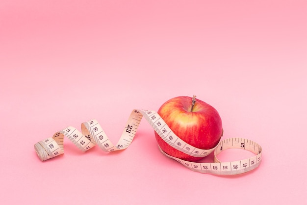 Maçã vermelha e fita métrica isoladas em fundo rosa Estilo de vida saudável Conceito de dieta Boa nutrição