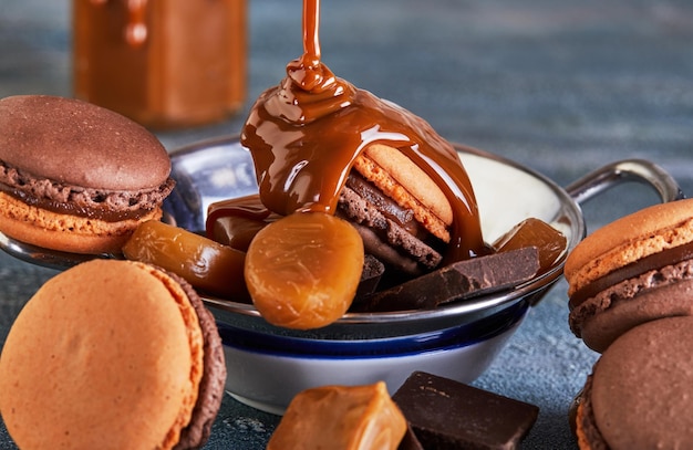 Macarões de chocolate com molho de caramelo e doces de chocolate em fundo castanho