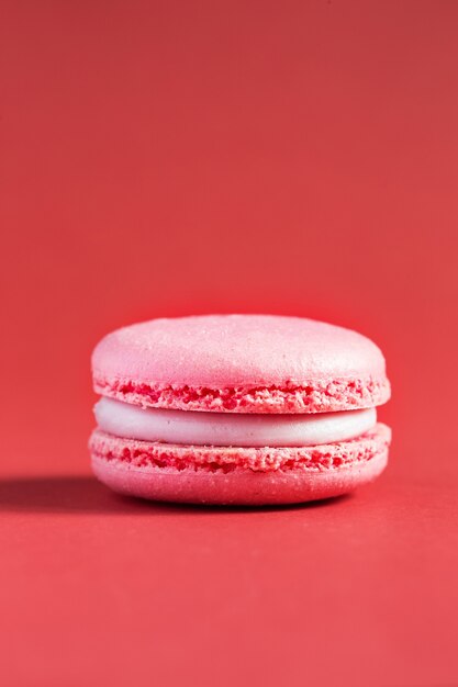 Macaron de bolo rosa ou macaroon na parede vermelha. biscoitos de amêndoa coloridos. Bolo de macaroon francês