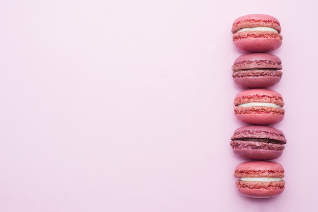 Macaron de sobremesa rosa ou macaroon na vista superior de fundo rosa com lay plana