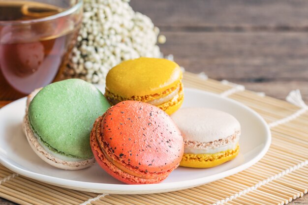 El macaron francés colorido o el macaron italiano en la placa blanca sirvió con té o café.