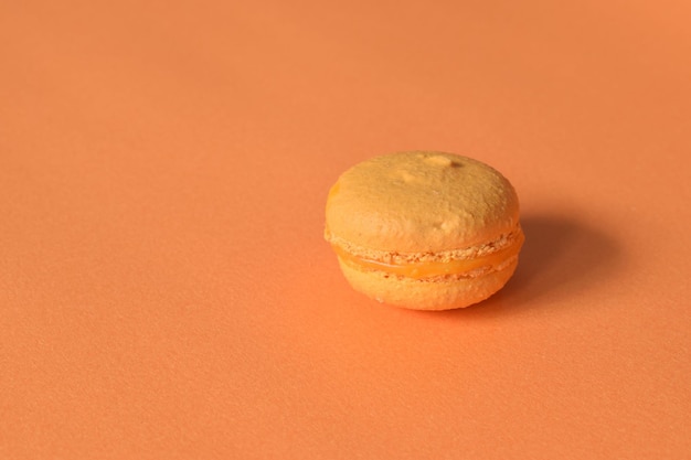 Un macaron naranja sobre un fondo naranja minimalista.