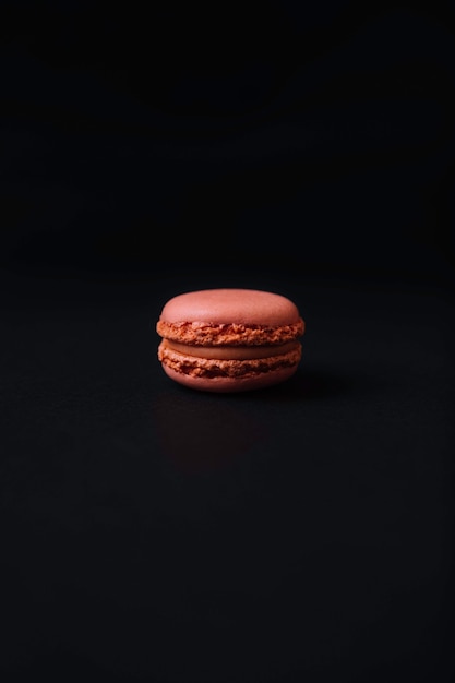 Macaron de sabor rosa y fresa sobre fondo negro