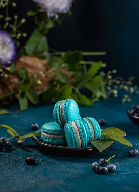 Macarones azules y moras sobre un fondo azul oscuro