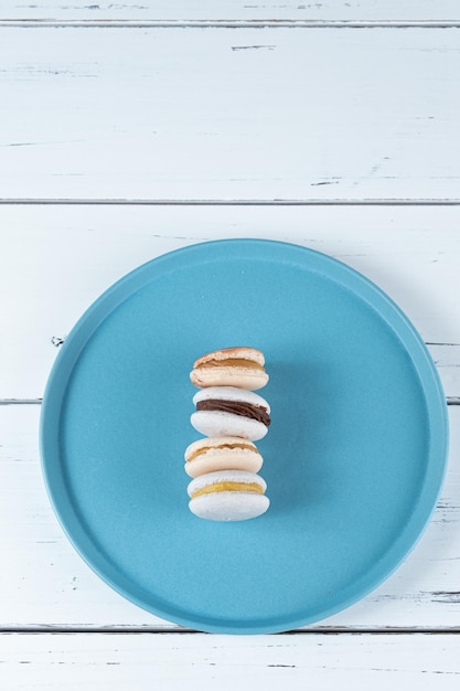 Macarones con relleno de ganache de chocolate y dulce de leche apilados en un plato azul vista