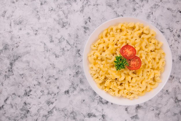 Macaroni e queijo num prato branco com salsa e cereja