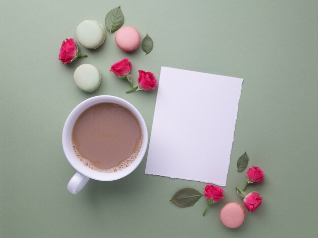 Macarons, café y rosa sobre fondo verde. Vista superior. Endecha plana