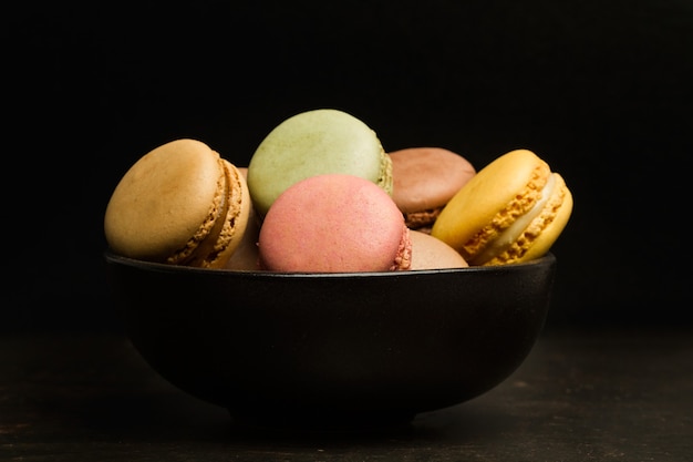 Macarons de colores en un tazón negro