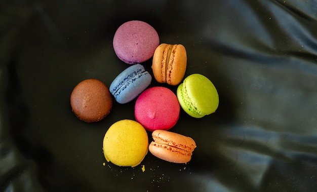 Foto macarons coloridos sobre fondo negro vista cercana