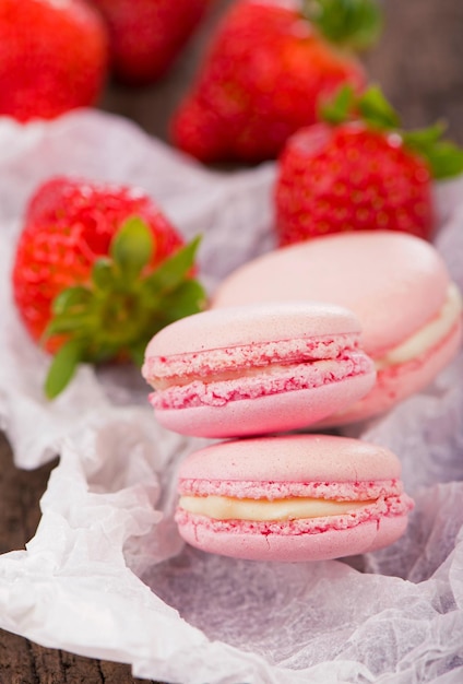 Macarons com morangos Macaroon com biscoitos de framboesas em um fundo de madeira