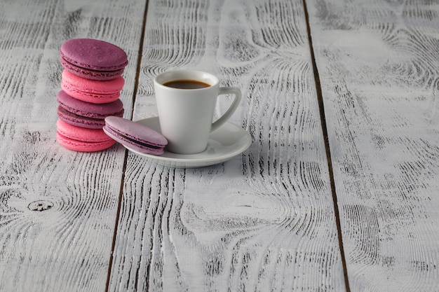 Macarons com uma xícara de café na mesa de madeira