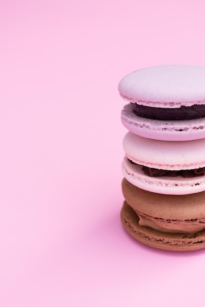 Macarons de pastelaria de cores diferentes em um fundo rosa