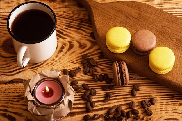 Macarons doces em tábua de madeira com xícara de café e vela acesa Foto atmosférica Conteúdo para redes sociais