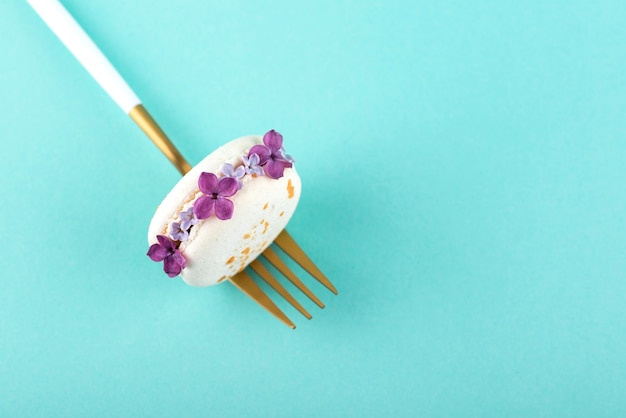 Macarons ecológicos planos leigos com flores sobre fundo azul