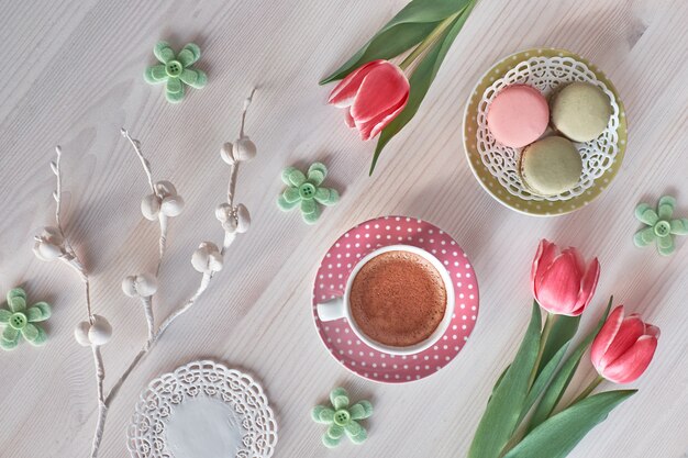 Macarons, espresso en taza rosa, fresias y tulipán rosa, vista superior