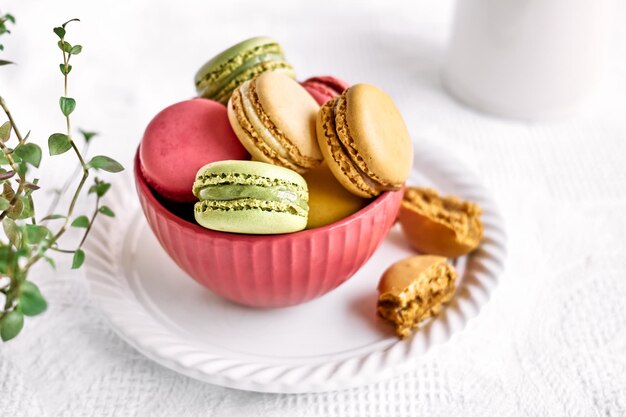 Foto macarons franceses coloridos em tigela rosa na toalha de mesa branca