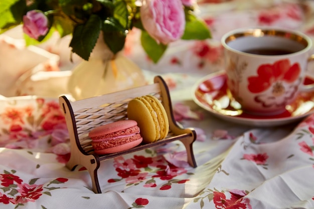Macarons franceses no banco de madeira e mesa em estilo café Decorações de rosas de chá Hora do chá
