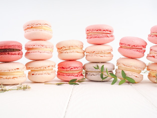 Los macarons franceses o italianos coloridos apilan en la tabla de madera blanca. Postre para servir con merienda o café