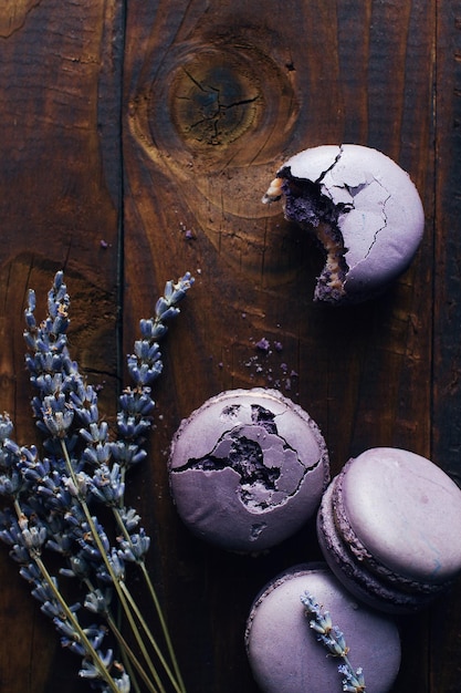 Macarons de lavanda púrpura o arándanos y lavanda seca sobre una mesa de madera oscura, sabroso postre francés