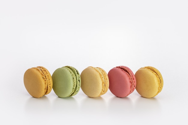 Macarons multicolores en una línea sobre una superficie clara