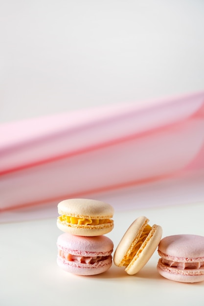 Macarons ou macarons franceses em tons pastel coloridos em fundo branco e rosa