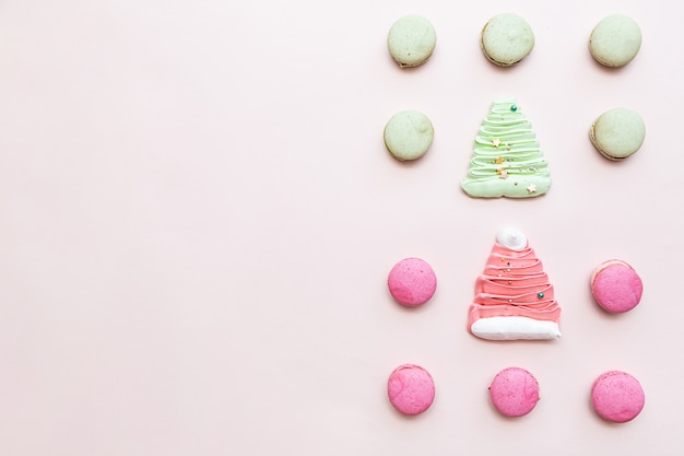 Macarons rosa y verde sobre el fondo de dulces de mesa rosa claro.