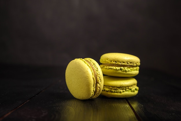 Macarons con sabor a pistacho sobre una mesa oscura