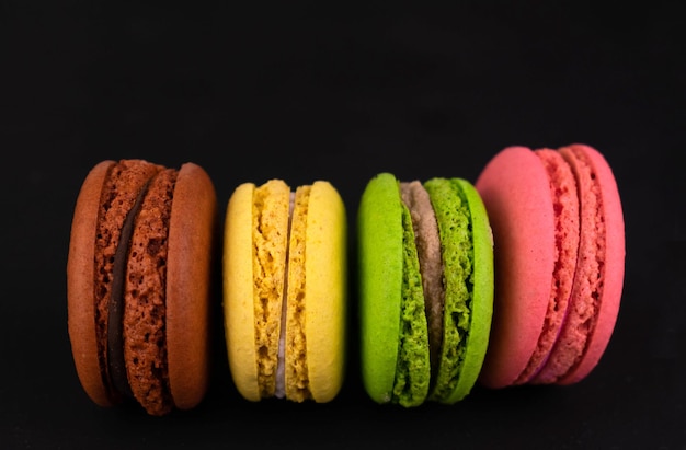 Macarons sobre un fondo negro Macarrones coloridos franceses Copie el espacio