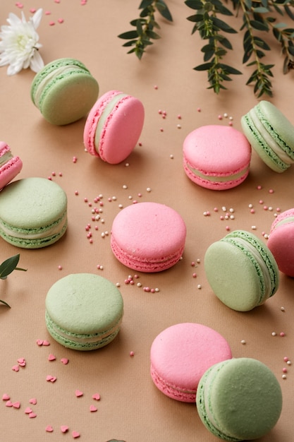 Macarons sorprendentemente tiernos colores verde y rosa cuidadosamente distribuidos sobre un fondo beige