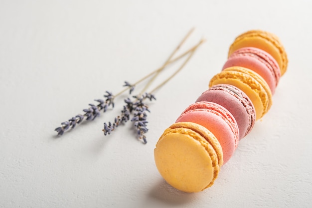 Macarons und Lavendelblüten auf weißer Oberfläche bunte französische Desserts selektiv