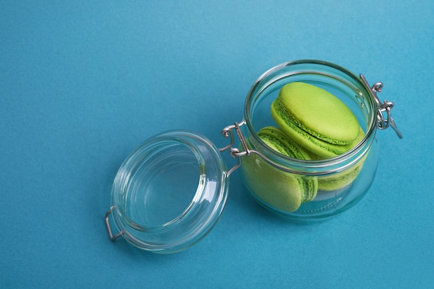 Macaroon verde sobre um fundo azul em uma jarra de vidro