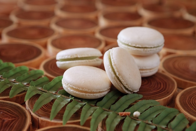 Macaroons brancos delicados e humildes sobre um fundo de madeira o tom pastel do creme dentro dos biscoitos franceses