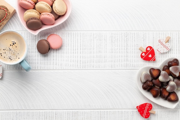 Macaroons caseiros, chocolate de coração e xícara de café. Vista superior plana com espaço de cópia. Dia dos Namorados.