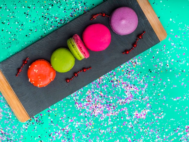 Foto macaroons coloridos em ardósia de pedra sobre fundo de cor verde menta na moda macarons doces com bagas vista superior