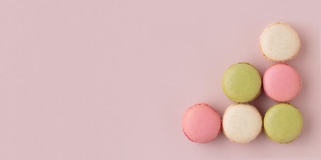 Macaroons coloridos em fundo rosa aumentam os lucros da produção de confeitaria