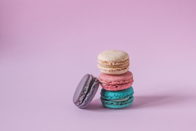 Macaroons coloridos em uma pilha isolada em um fundo rosa. Copiar espaço