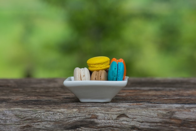 Foto macaroons coloridos no prato na mesa de madeira