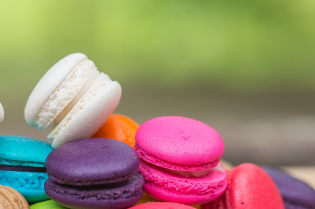 Macaroons coloridos no prato na mesa de madeira