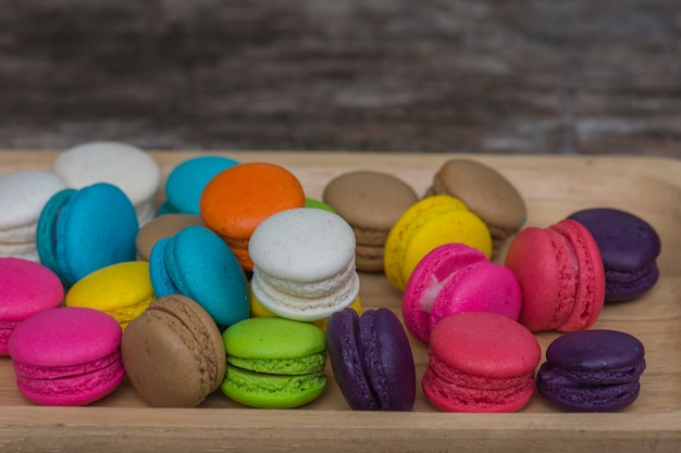 Macaroons coloridos no prato na mesa de madeira