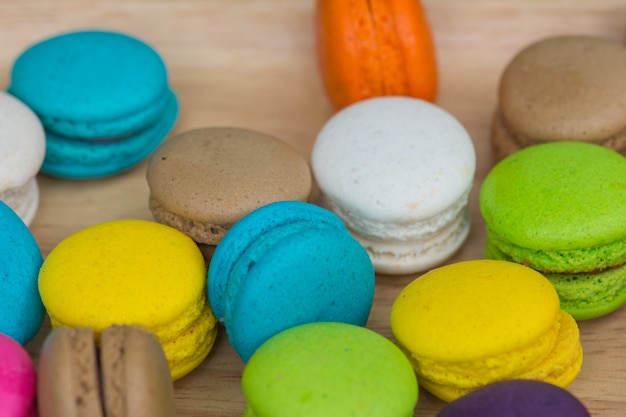 Macaroons coloridos no prato na mesa de madeira