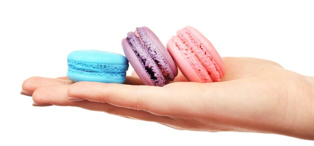 Macaroons coloridos saborosos na mão feminina isolados em branco