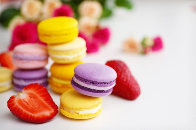 Macaroons com rosas e morangos no fundo branco