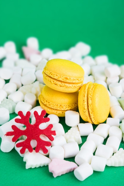 Macaroons de amarelo, marshmallow e flocos vermelhos em verde