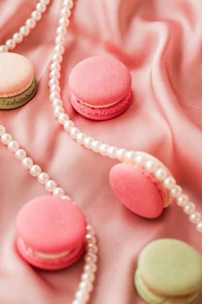 Macaroons doces e joias de pérolas em fundo de seda joias chiques parisienses comida de sobremesa francesa e bolo macaron para presente de feriado de marca de confeitaria de luxo