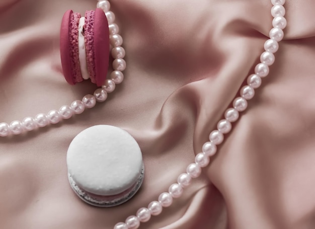 Macaroons doces e joias de pérolas em fundo de seda joias chiques parisienses comida de sobremesa francesa e bolo macaron para presente de feriado de marca de confeitaria de luxo