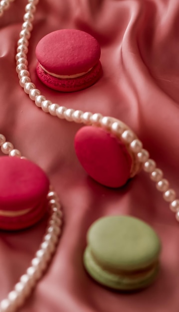 Macaroons doces e joias de pérolas em fundo de seda joias chiques parisienses comida de sobremesa francesa e bolo macaron para presente de feriado de marca de confeitaria de luxo